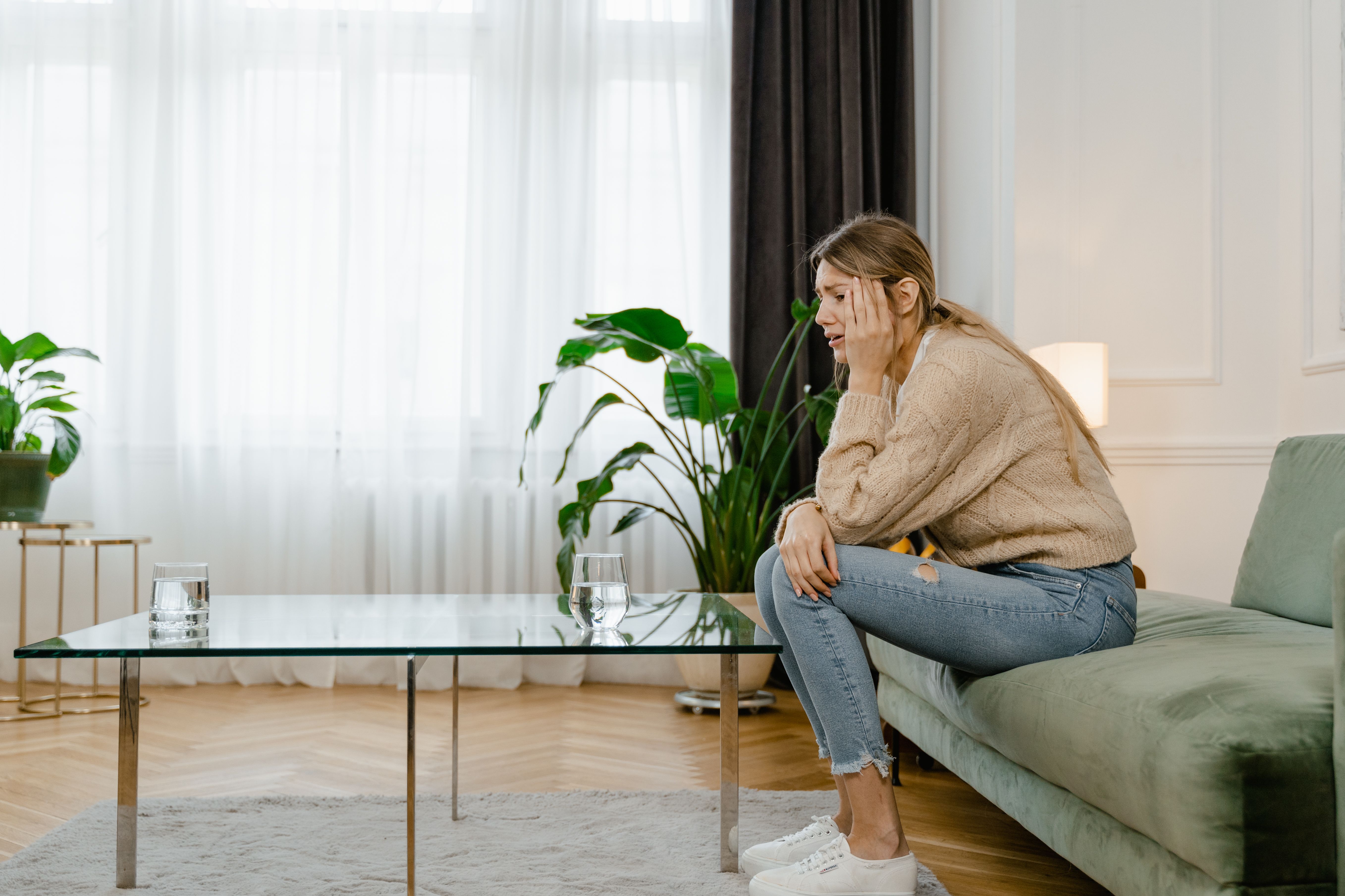 Patient sitting by the window feeling emotionally exhausted before finding relief with TMS therapy.